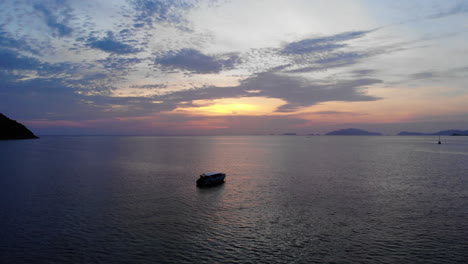 Drone-footage-of-boats-anchored-on-a-peacefull-ocean-with-a-coloful-sunset-on-the-background