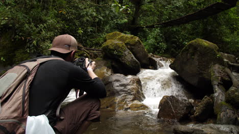 Photographer-Taking-Pictures-of-a-River-Running-Under-a-Bridge-in-the-Jungle