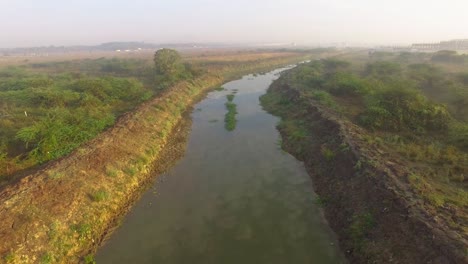 Drone-shot-moving-forwards-above-a-river-on-a-foggy-morning-showing-reflection-of-sky-on-the-river