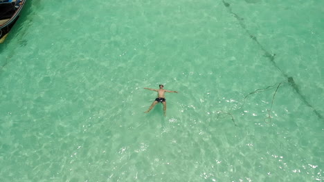 Man-floating-and-resting-in-clear-ocean-water