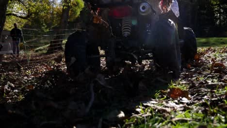 Quad-bike-moving-in-slow-motion-close-up-shot-with-child-driving-doing-drifts-spraying-mud-and-leaves-towards-the-camera