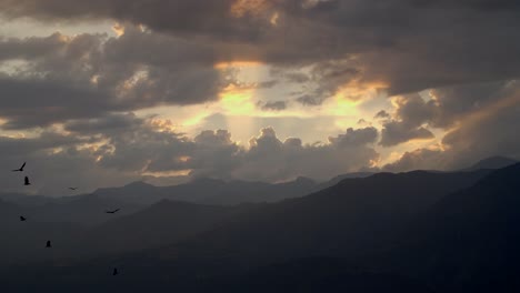 Sunset-with-Sunrays-with-Silhouetted-Birds-Gliding-Around-in-the-Andes-Mountains