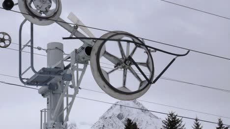 close-up-shot-of-a-ski-lift-wheel-moving-with-cloudy-day-mountain-backdrop-4k