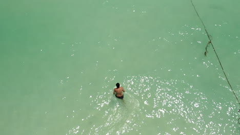 Top-view-of-a-man-walking-to-the-ocean-for-a-freestyle-swim