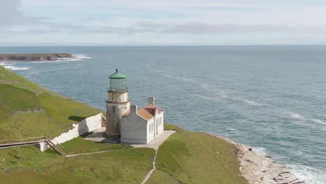 Historic-lighthouse-on-cliff-side,-aerial-push-in-shot