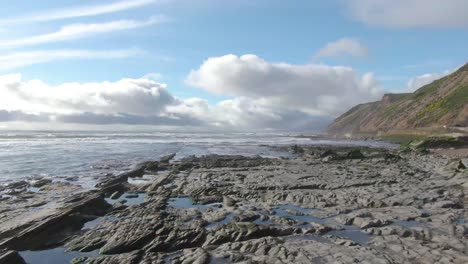 Low-drone-shot-over-scenic-ocean-rocks