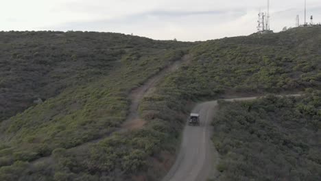 Toma-Aérea-De-Un-Jeep-Y-Un-Coche-Conduciendo-Por-La-Montaña-Hasta-El-Océano