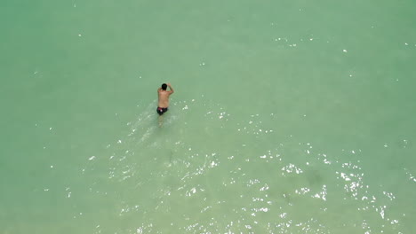 Top-view-of-a-man-walking-and-swimming-freestyle-on-the-ocean