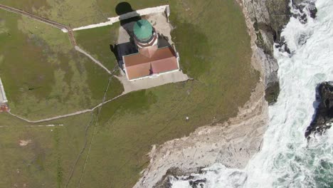 Historic-lighthouse-on-coastal-cliffs,-overhead-shot