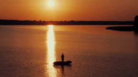 Luftaufnahme-Von-Männern,-Die-Abends-Vor-Strahlender-Sonne-Vom-Boot-Aus-Fischen
