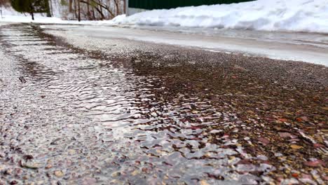 Snow-melting-and-flowing-down-asphalt-driveway