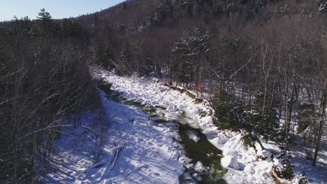 Schwenken-Und-Aufsteigende-Drohnenaufnahme-Eines-Eisigen-Und-Fließenden-Winterflusses