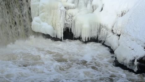 Gezoomt-Im-Hinblick-Auf-Einen-Wasserfall,-Der-In-Zeitlupe-über-Eisbedeckte-Felsen-Fällt