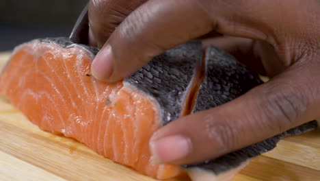 A-close-up-side-view-shot-of-raw-fish-being-sliced-on-a-chopping-board-in-slow-motion