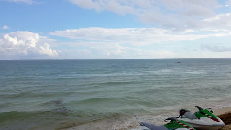 Zwei-Jetskis-Sitzen-Am-Strand-Mit-Blick-Auf-Den-Blauen-Ozean-An-Einem-Sonnigen-Tag-In-Mexiko