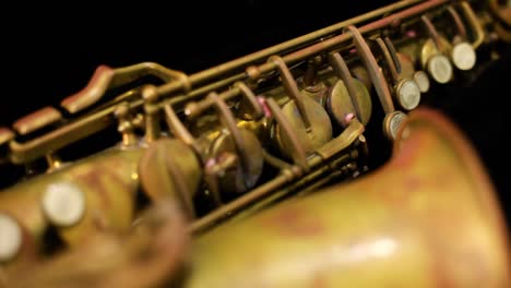 Dolly-shot-of-a-very-old-rusty-alto-saxophone-with-black-background