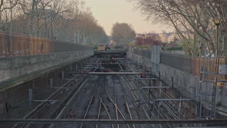 Pan-down-of-a-train-moving-slowly-into-frame-on-the-railway-lines-in-the-middle-of-the-city-of-Paris-in-France