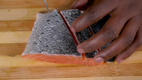 A-medium-shot-from-the-top-of-a-chef-slicing-a-piece-of-raw-fish-on-a-chopping-board-in-slow-motion