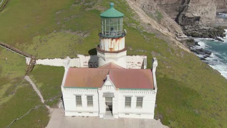 Historic-lighthouse-on-coastal-cliffs,-aerial-descent-with-tilt