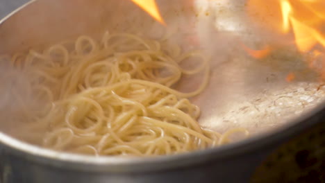 A-close-up-of-flambe-pasta-being-tossed-in-a-pan-in-slow-motion