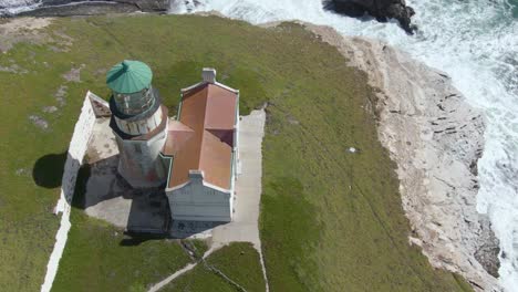 Historic-lighthouse-on-cliff-side,-drone-descent