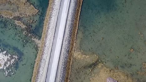 a-flyover-of-an-Icelandic-road-surrounded-by-crystal-clear-glacier-water