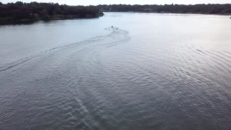 A-slo-motion-aerial-shot-of-some-people-having-fun-being-pulled-behind-a-jet-ski-on-a-tube-in-a-lake-in-florida