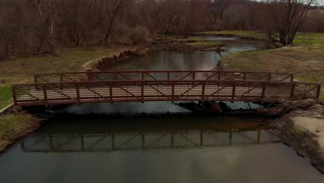 Drone-view-of-a-footbridge-crossing-a-beautiful-twisting-river