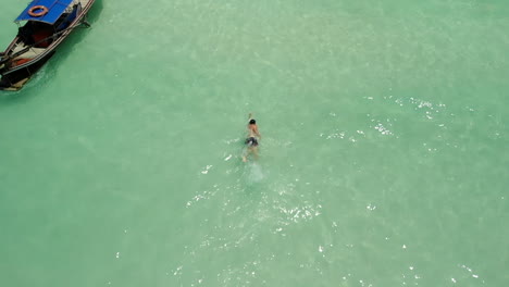 Hombre-Nadando-En-Estilo-Libre-En-Aguas-Limpias-De-Ocan-Cerca-De-Un-Barco-En-Tailandia