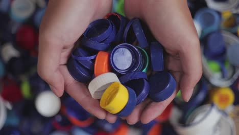 Hands-cupping-pile-of-plastic-bottle-caps-and-put-them-away