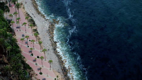 Top-down-birds-eye-aerial-view-of-the-waves-crashing-on-a-rocky-Southern-California-beach