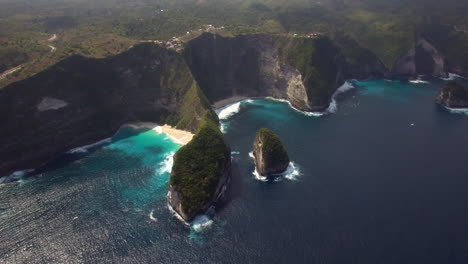 drone-flying-up-tilt-down-above-kelingking-beach-on-nusa-penida-island-over-the-seashore-green-peninsula-yellow-sand