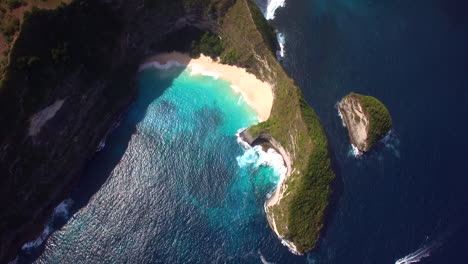 drone-flying-forward-above-the-kelingking-beach-on-nusa-penida-island-green-peninsula-yellow-sand