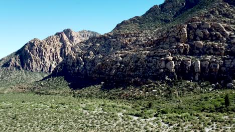 Sobrevuelo-Directo-De-Drones-Sobre-El-Suelo-Del-Valle-Cubierto-De-Vegetación-Y-La-Ladera-De-La-Montaña-En-El-área-De-Conservación-Nacional-Del-Cañón-De-Roca-Roja-Las-Vegas-Nevada