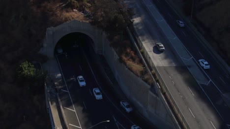 Drohnenaufnahme-Des-Verkehrs-In-Los-Angeles,-Der-In-Die-Tunnel-Nördlich-Der-Stadt-Ein--Und-Ausfährt