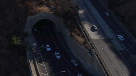 Drohnenaufnahme-Des-Verkehrs-In-Los-Angeles,-Der-Auf-Einer-Brücke-Und-Aus-Einem-Tunnel-Herausfährt