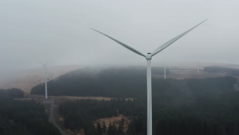 Gloomy-tracking-aerial-shot-from-left-to-right-of-wind-farm-turbines-in-heavy-cloud-and-rain-on-the-Rhigos-moutainside-of-the-Welsh-Valleys