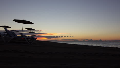 Sonnenaufgang-Am-Strand-Im-Zeitraffer-Mit-Sonnenschirmen-In-Spanien