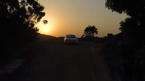 Drone-rising-upwards-and-forwards-past-a-Honda-civic-car-to-reveal-vast-openness-with-a-sunset