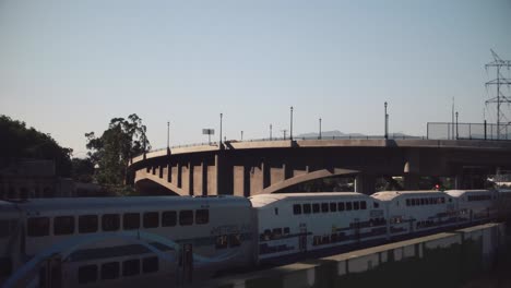 Drone-shot-of-a-Los-Angeles-Metro-train-going-on-a-bridge-over-the-LA-river-in-Los-Angeles,-California