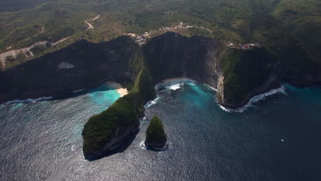 drone-flying-forward-above-kelingking-beach-on-nusa-penida-island-over-the-seashore-green-peninsula-yellow-sand