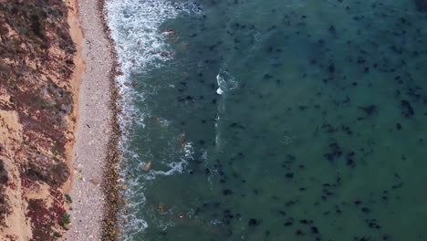 Top-down-birds-eye-aerial-view-of-the-waves-crashing-on-a-rocky-Southern-California-beach