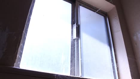 Verlassenes-Fensterlicht,-Das-Durch-Spinnweben-Scheint,-Schwenkt-Gruselig-Aus-Der-Nähe-Nach-Unten
