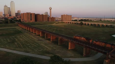Güterzug-Fuhr-Bei-Sonnenuntergang-In-Die-Innenstadt-Von-Dallas,-Texas-Reunion-Tower-Und-Die-Skyline-Der-Stadt-Im-Hintergrund