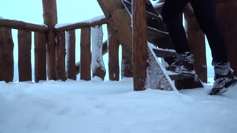 Männliche-Füße,-Die-Holztreppen-Auf-Der-Aussichtsplattform-Hinuntergehen,-Im-Winter-Eingeschneit