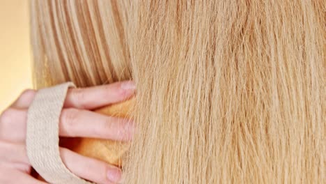 Close-up-of-the-straight-blond-hair-of-a-young-woman-while-brushing-their-natural-brush