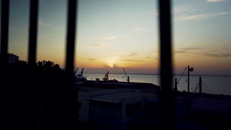 Hafen-Sonnenaufgang-Lissabon-Morgendämmerung-Mit-Kranichsilhouette-Durch-Rostige-Zäune