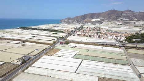 Aerial-view-of-a-town-in-the-mediterranean-coast-surrounded-by-white-greenhouses