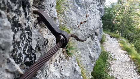Iron-twisted-rope-stretched-between-rocks-near-footpath-in-the-mountains