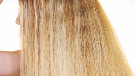 Beautiful-blond-woman-with-long-straight-hair-brushes-it-with-a-natural-brush